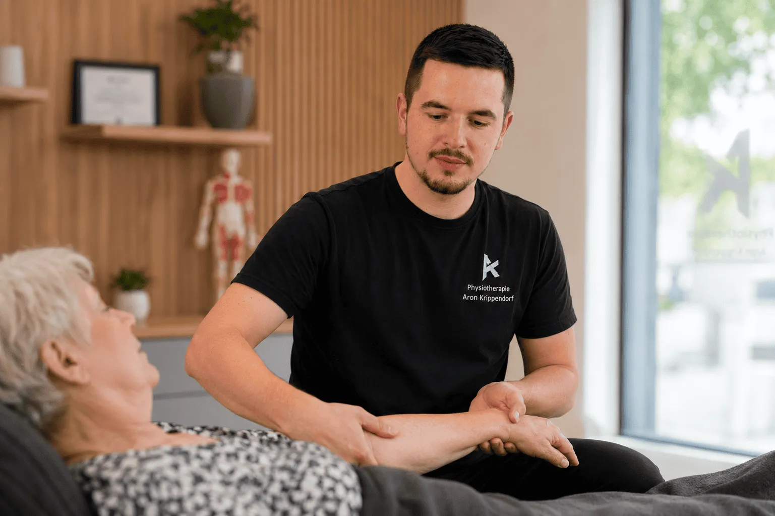 Therapeut der Praxis Aron Krippendorf behandelt eine Seniorin